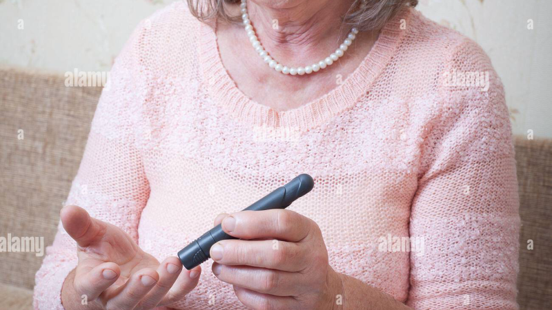 person checking blood glucose with glucometer on table