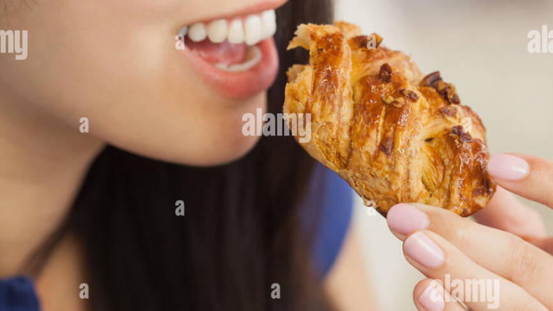 person eating a sugary breakfast pastry with coffee