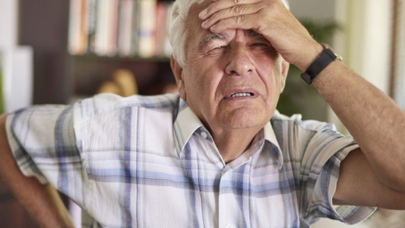 senior person holding head with expression of confusion, brain fog concept