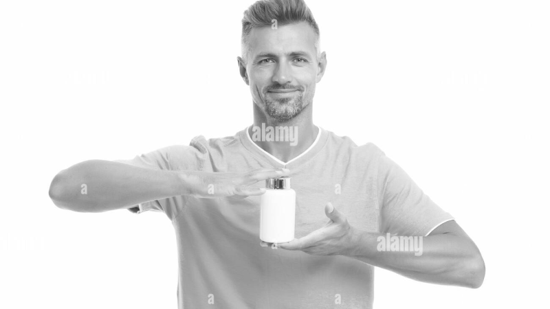 person holding bottle of supplements and prescription pill bottles on table