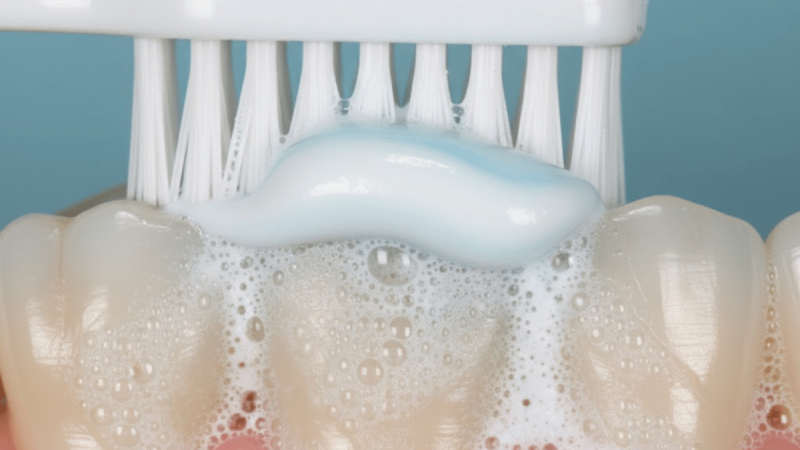 person brushing teeth with fluoride toothpaste, close-up of toothbrush