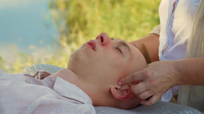 person massaging temple near ear
