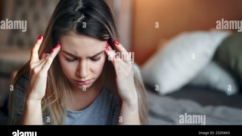 person covering ears in frustration while sitting on bed