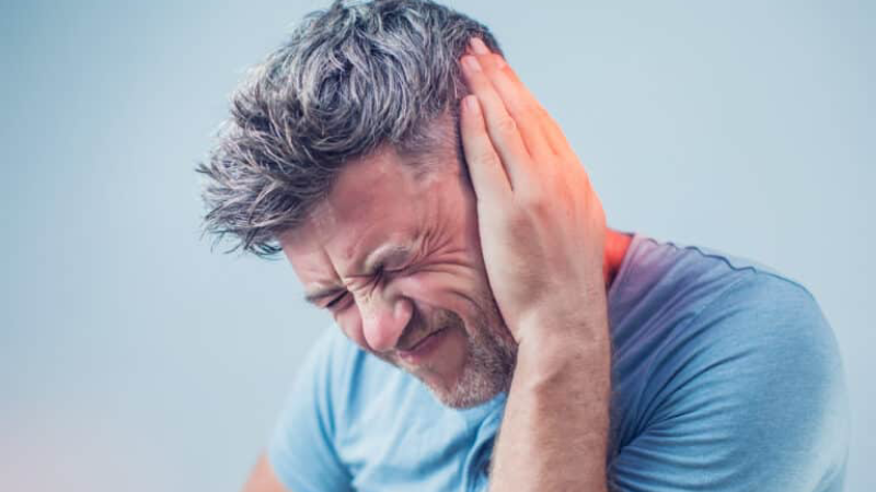 Person covering ears with strained expression, illustrating tinnitus frustration