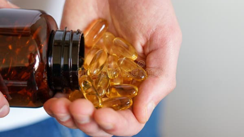 person holding supplement bottle with capsules