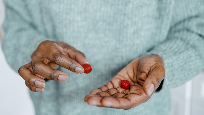 person taking gummy supplement with glass of water