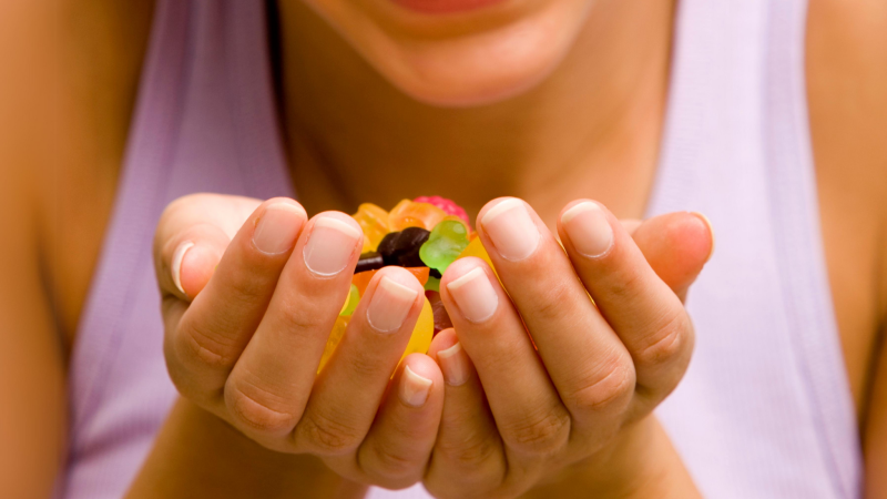 woman taking a supplement gummy in front of a kitchen window
