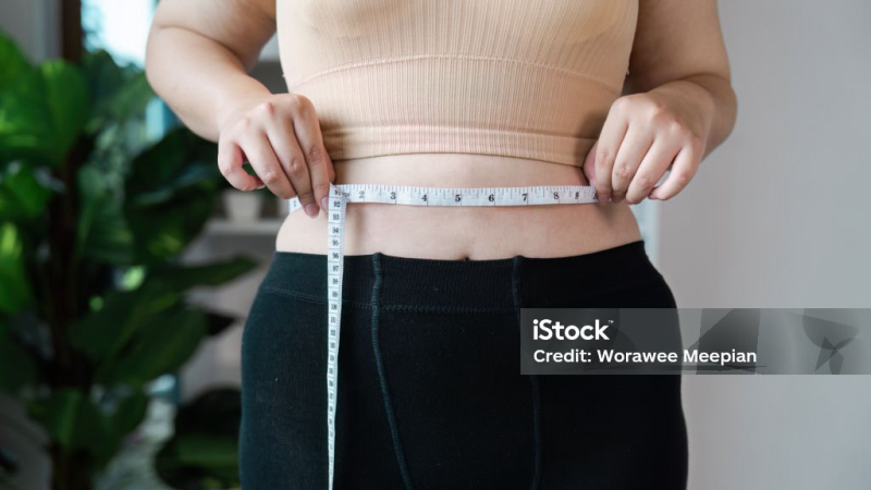 person measuring waist with tape measure