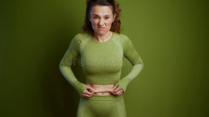 woman holding stubborn belly fat looking frustrated